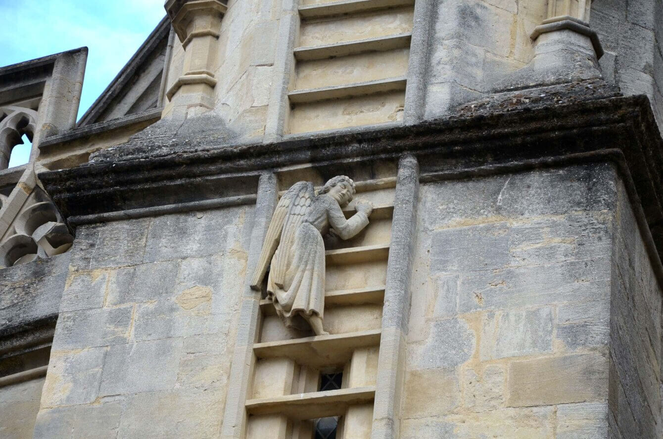 Statue d’un ange grimpant une échelle sur la façade de l’abbaye