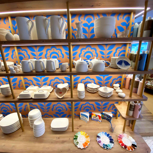 Étagère sur laquelle sont diposés une grande variété de pièces en faïence disponibles pour la peinture.